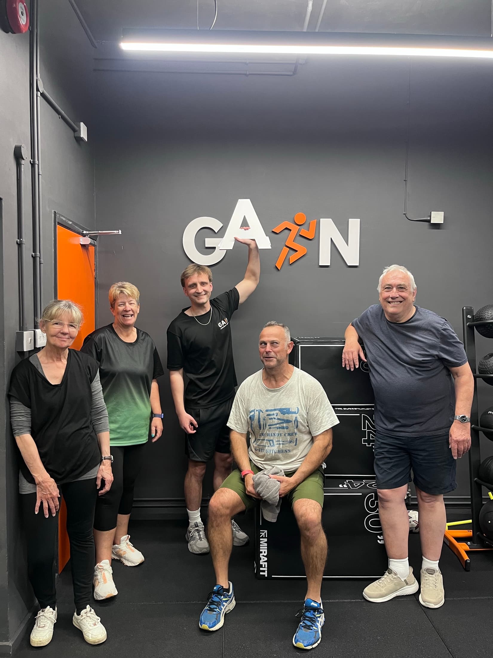 Hallum and four members smiling in front of the GAIN sign