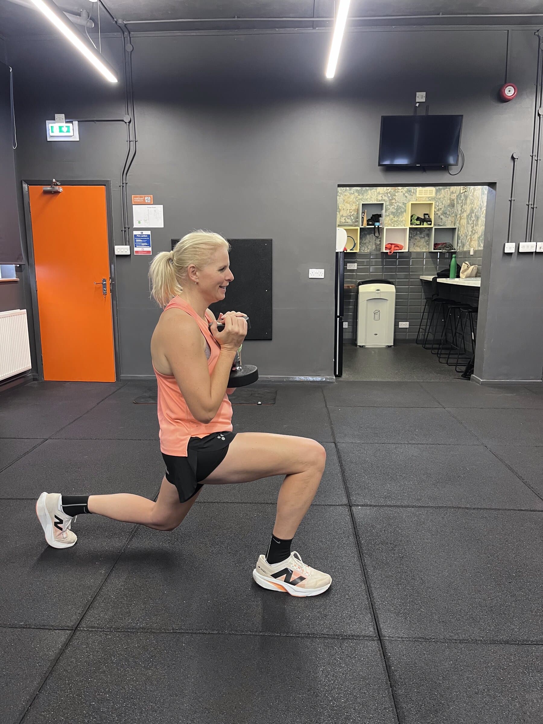 Senior female member performing a dumbbell lunge
